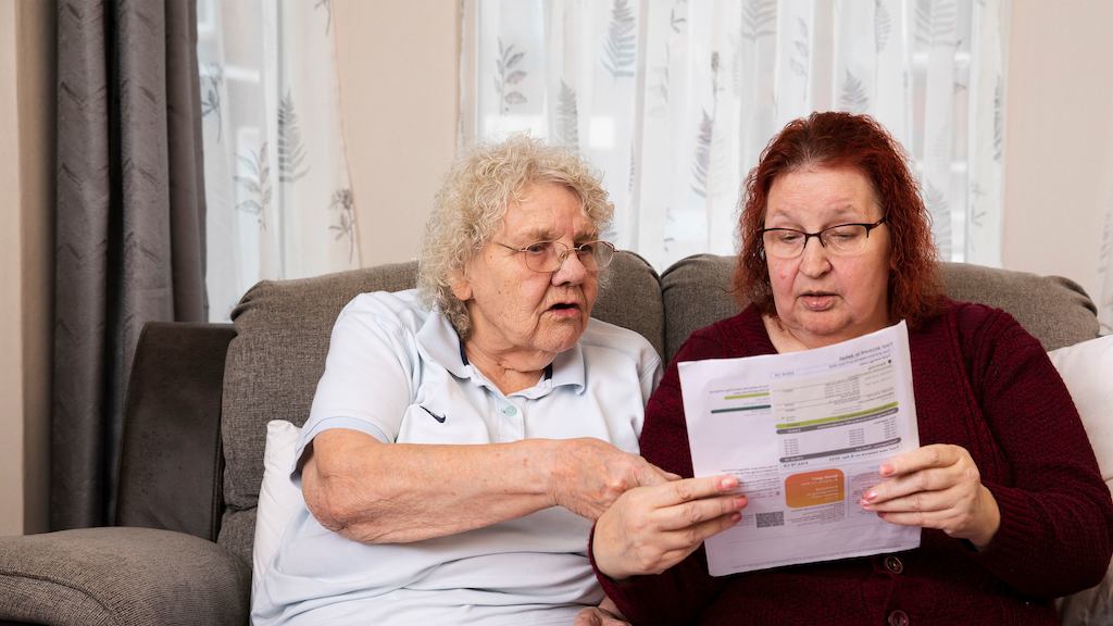 Two older women looking at bills together